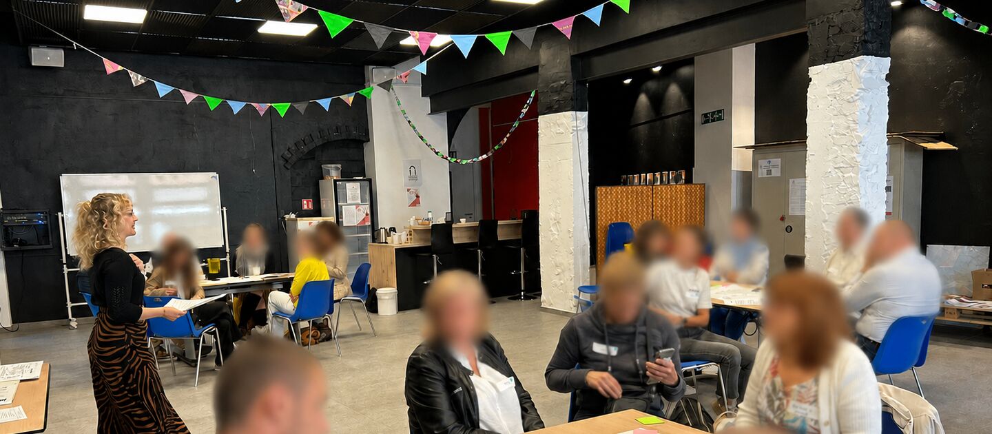Ann Backes anime un atelier collectif en entreprise à Liège, les participants travaillent en sous-groupes.