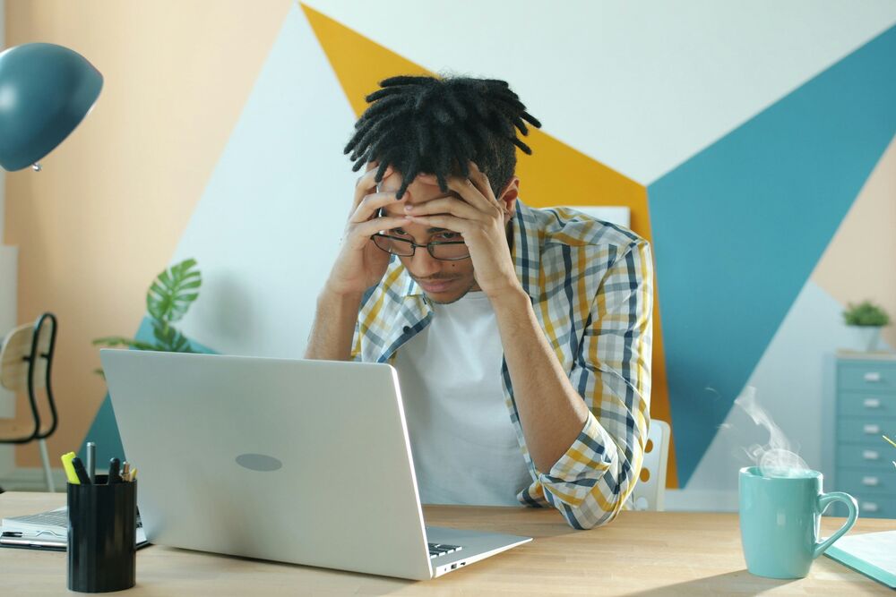 Homme stressé devant son ordinateur, tête entre les mains