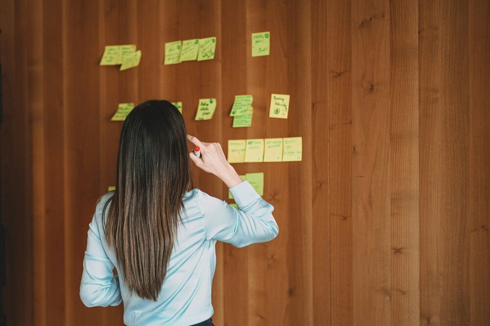 Une personne organise des post-it sur un mur, symbolisant la mise en clarté de son profil professionnel